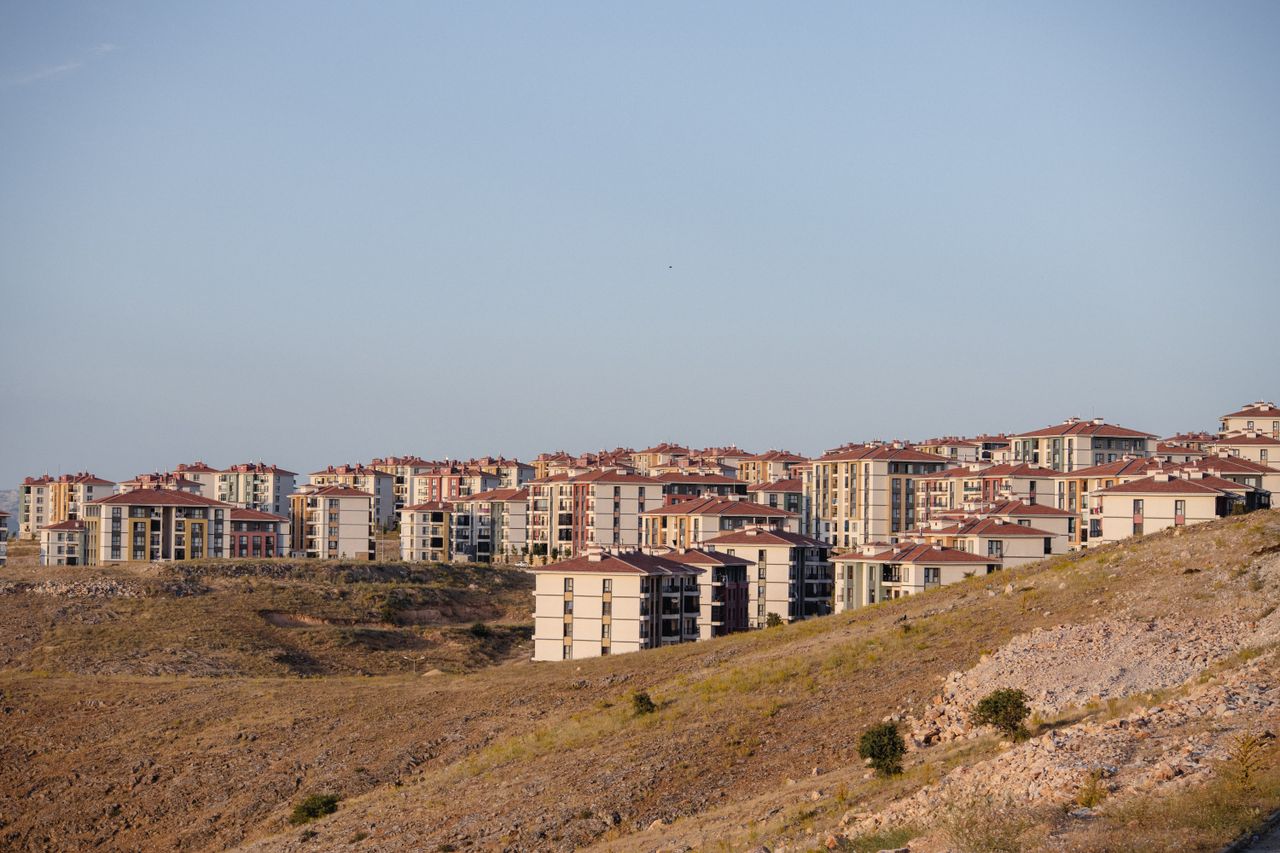 A cluster of modern residential buildings on a hilly landscape during the day.